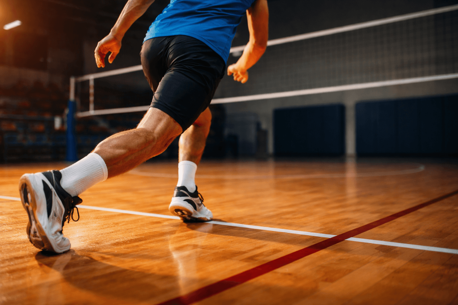 Volleyball athlete practicing approach footwork on a marked indoor court.